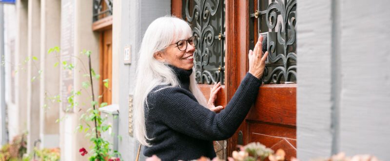 Elegant woman using smart lock to unlock door at Airbnb property entrance