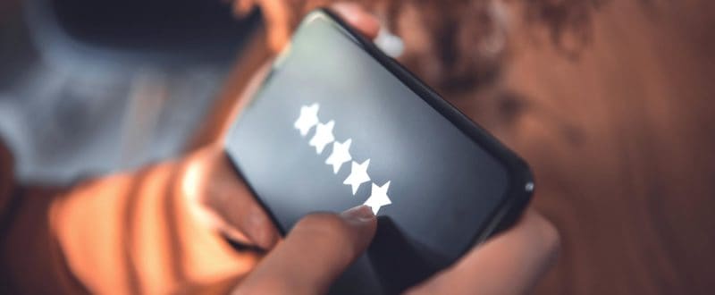 A women's hands hold mobile phones leaving a hotel a 5-star review enhancing the hotels reputation