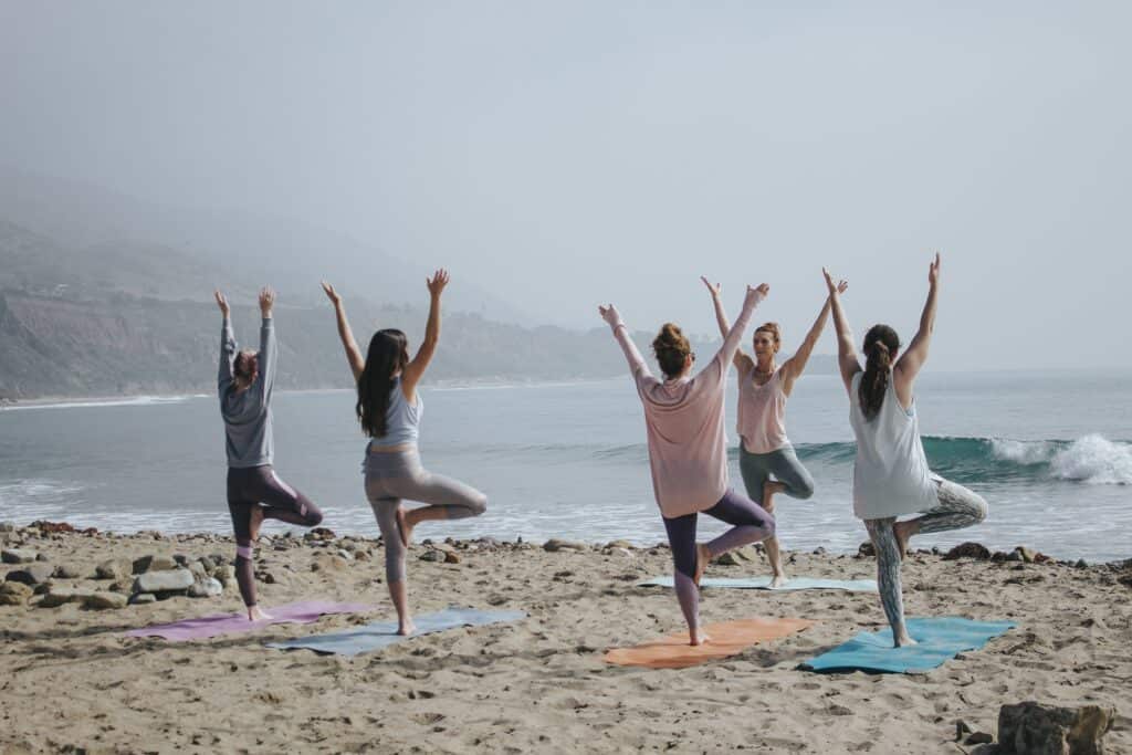 A group of guests enjoy a yoga session at the beach as part of their hotel's focus on a wellbeing experience.