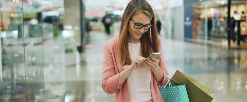 A traveler, while out shopping. uses SMS to communicate with her accommodation provider from her smartphone.