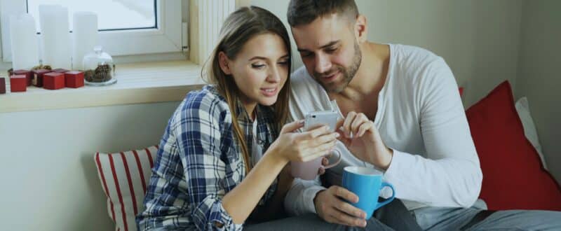 A pair of travelers use their mobile phone to research and book a trip in January.
